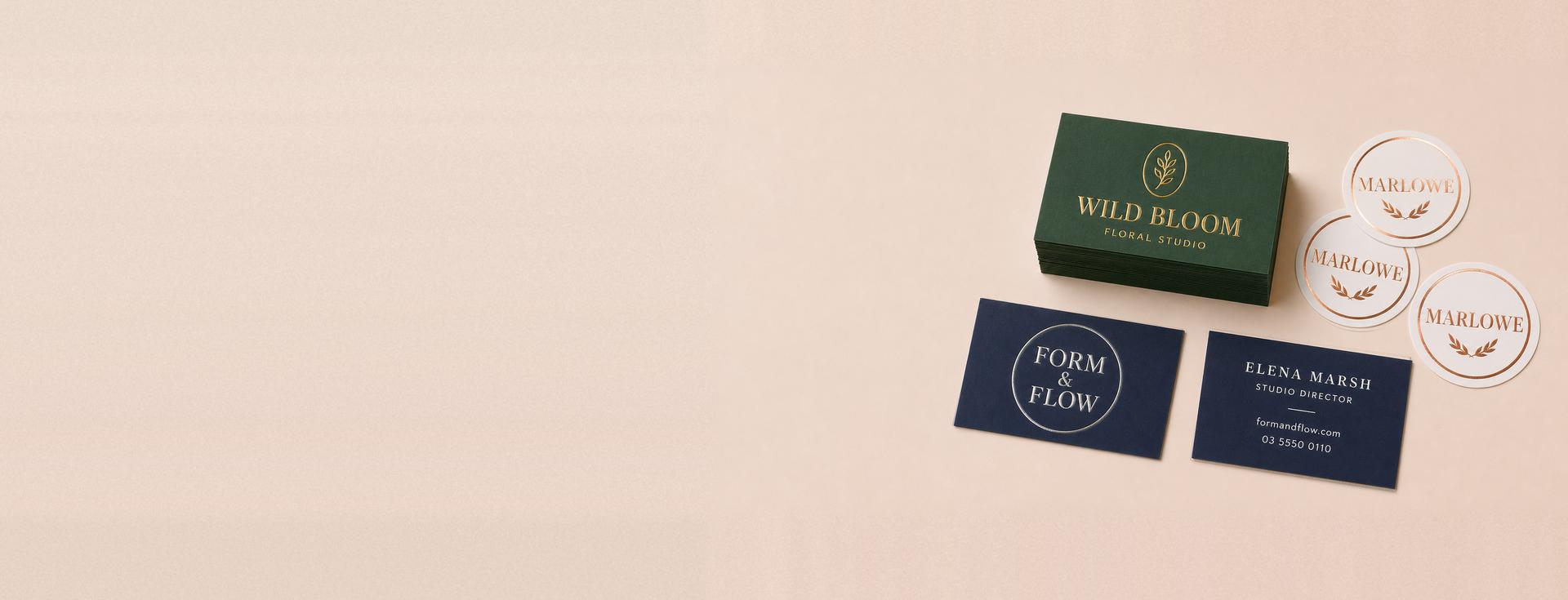 Flat foil business cards on navy and green stock with matching rose gold foil stickers, showing the foiled front and the printed back
