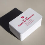 Vertical-format business cards printed on white linen stock with rounded corners, a portrait layout that stands out in a stack