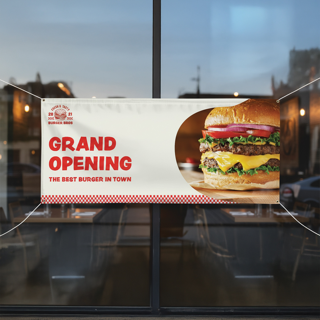 Printed vinyl banner advertising a grand opening, mounted outdoors with vivid full-colour graphics