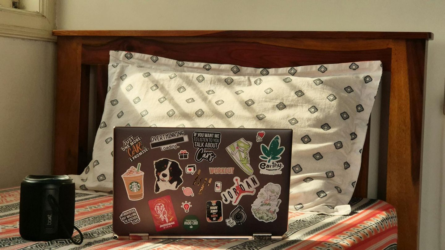 Close-up overhead view of A4 sticker sheet artwork on a laptop screen showing die-cut paths as coloured outlines around individual sticker d