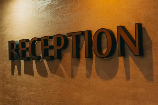 Custom acrylic reception panel sign mounted on a corporate office feature wall with standoff fixings