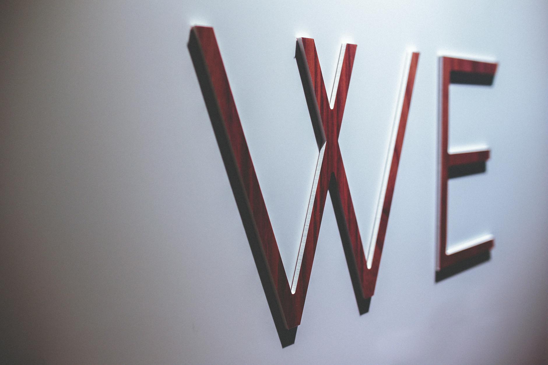 Raised acrylic cut letters spelling out a company name on a dark feature wall in a modern office