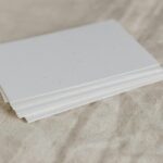 Fanned stack of clean, modern standard business cards on a timber desk, showing professional double-sided printing with a minimal design