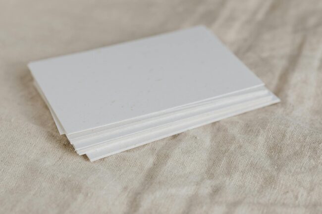 Fanned stack of clean, modern standard business cards on a timber desk, showing professional double-sided printing with a minimal design