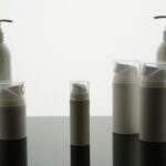 Overhead flat-lay of glass skincare bottles and kraft mailer pouches with clear transparent product labels applied, showing the no-label loo