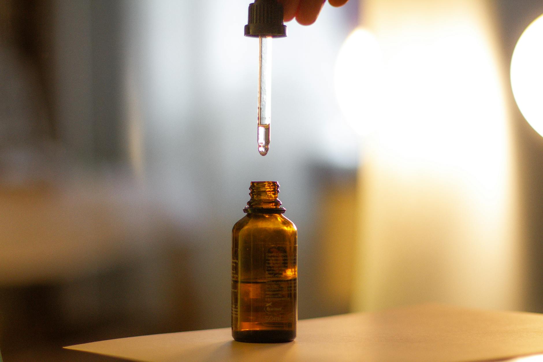Close-up of a clear label applied to an amber glass dropper bottle showing a botanical brand logo in full colour with white ink underprint,