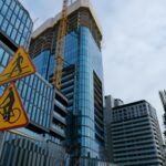 Construction site project signboard on hoarding fence showing builder company branding and project details, clear daylight, Australian urban