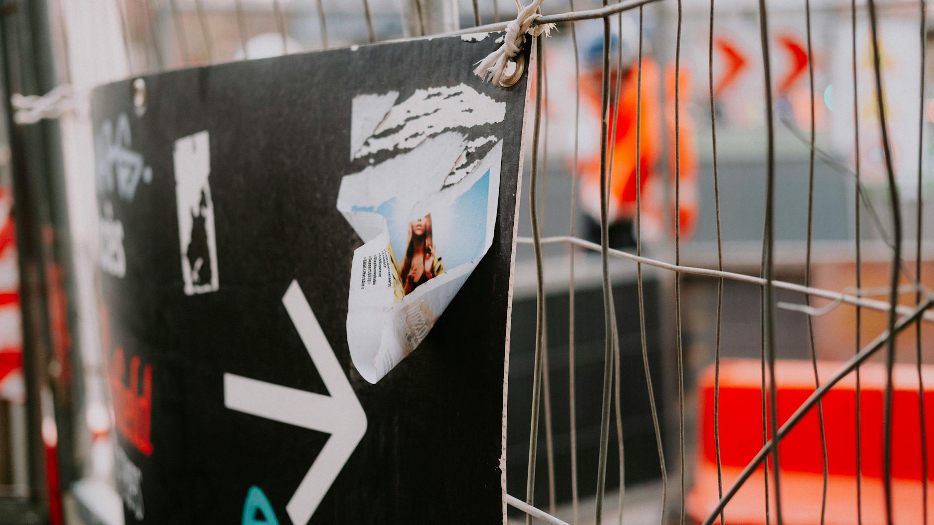 Mesh banner wrap on temporary security fencing around a construction site showing large-format developer branding and project render, urban