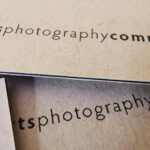 Side-by-side comparison of three consultant business card finishes on a neutral surface: a standard matte card with navy typography, a spot