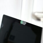 close-up of a small brand sticker on the back of a laptop surrounded by other creative stickers at a co-working space