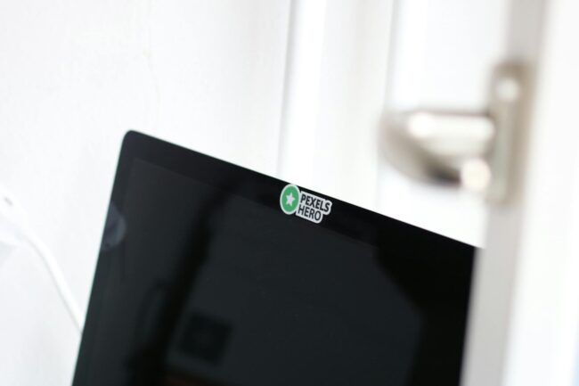 close-up of a small brand sticker on the back of a laptop surrounded by other creative stickers at a co-working space