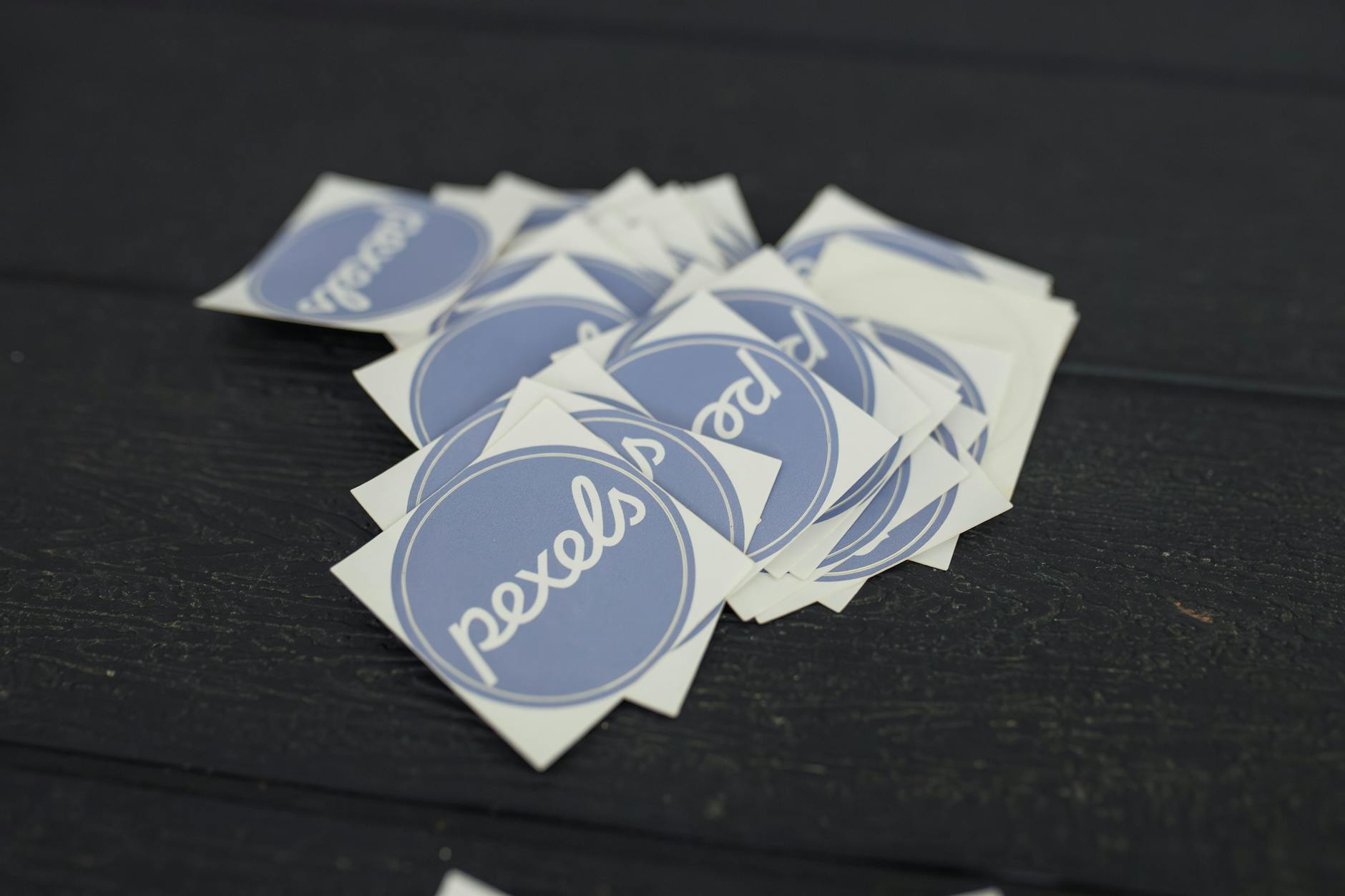 Flat lay of custom-printed logo stickers in various shapes and finishes arranged on a clean white surface with a coffee cup and kraft paper