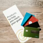 Three business cards arranged side by side on a dark textured surface showing a rose gold flat foil botanical border design, a standard gold