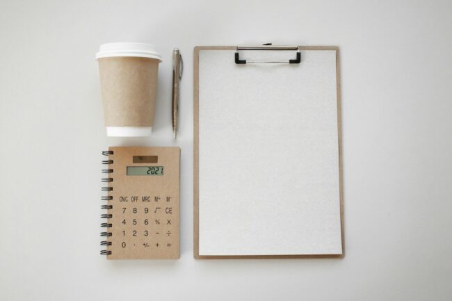 Overhead flat-lay of a single clean white business card with minimal black typography on a light timber surface, no props