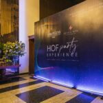 Elegant indoor event hall with a branded decorative backdrop and floral display for a gala evening