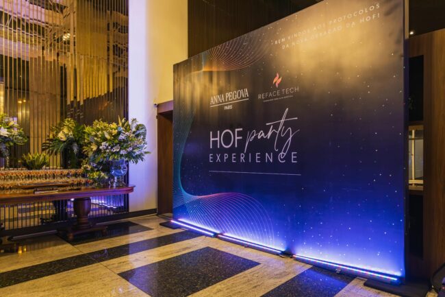 Elegant indoor event hall with a branded decorative backdrop and floral display for a gala evening