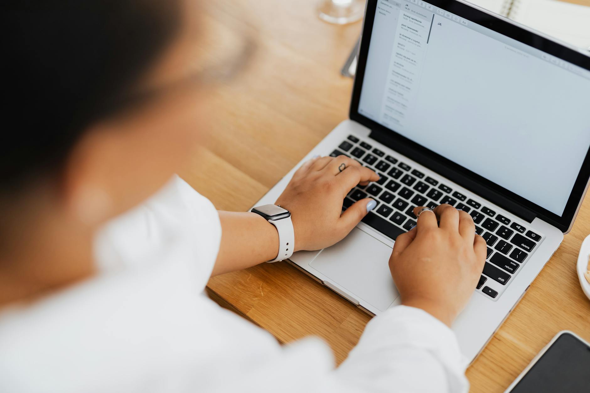 person writing a personalised follow-up email at a clean desk with a small collection of networking event business cards organised neatly ne