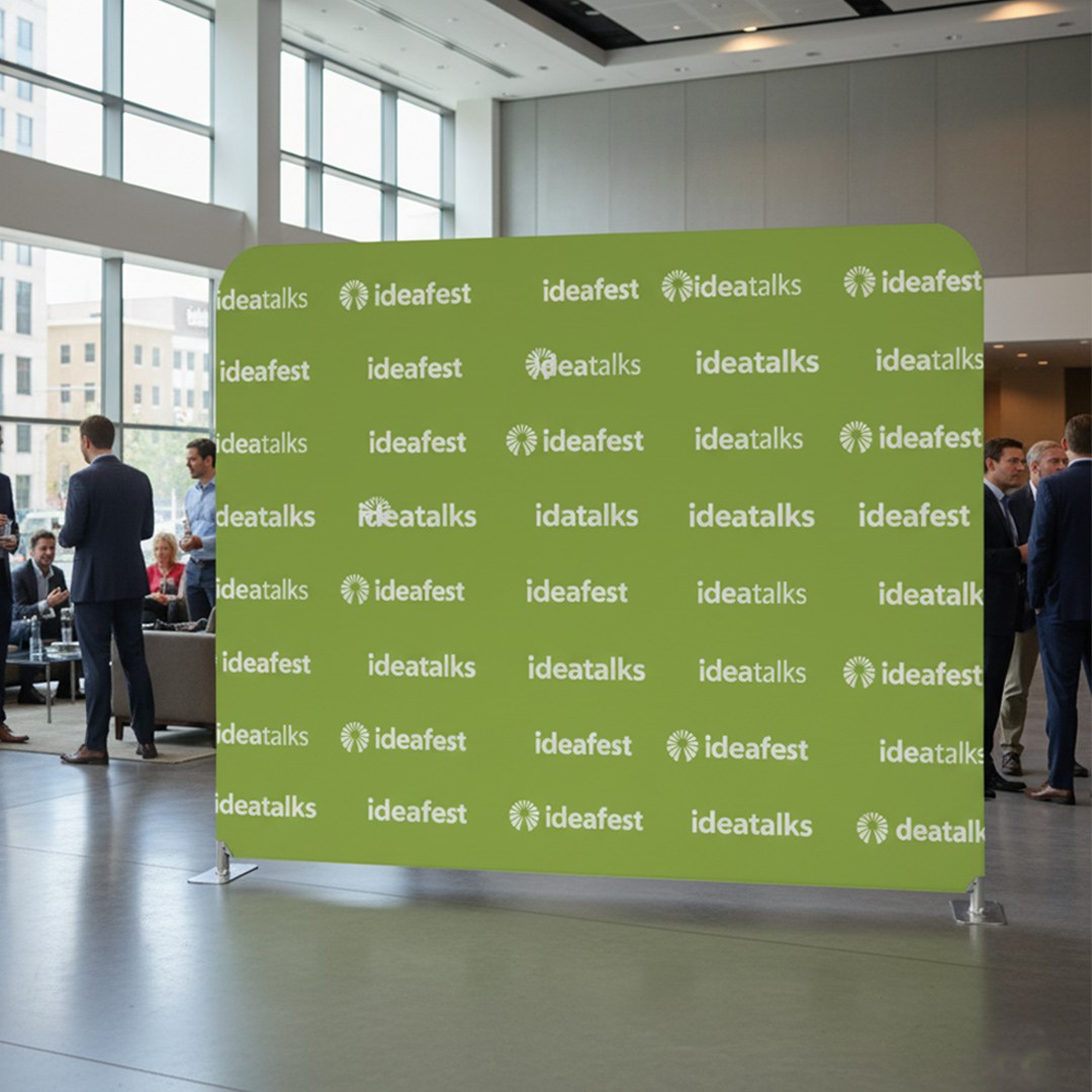 Paperlust step-and-repeat media wall at a corporate networking event with repeating green ideafest and ideatalks logos printed on stretch fabric.