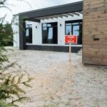 Real estate A-frame sign with bold agent branding on a suburban street, 600x900mm metal frame, professional full-colour print