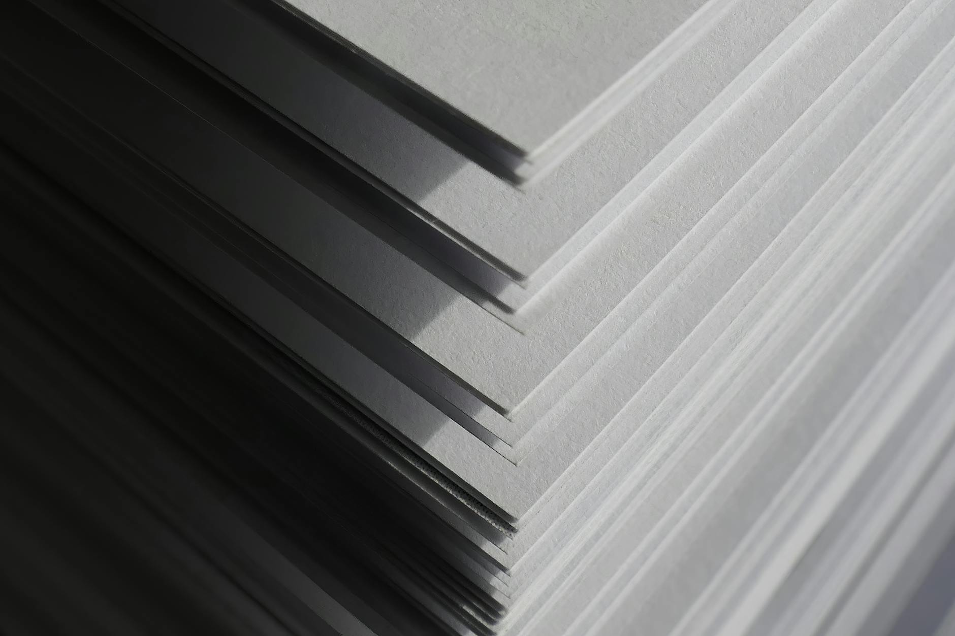 Flat lay or workshop shot of a batch of freshly printed real estate corflute signs stacked and ready for dispatch, showing multiple property