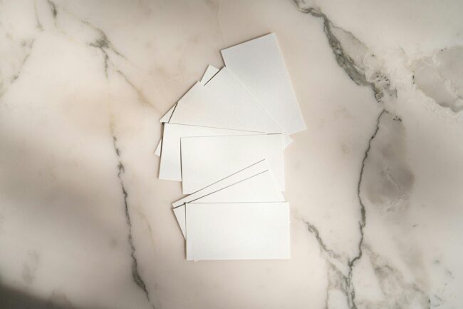 Close-up of square and standard rectangular business cards laid side by side on a white surface showing the size and shape contrast