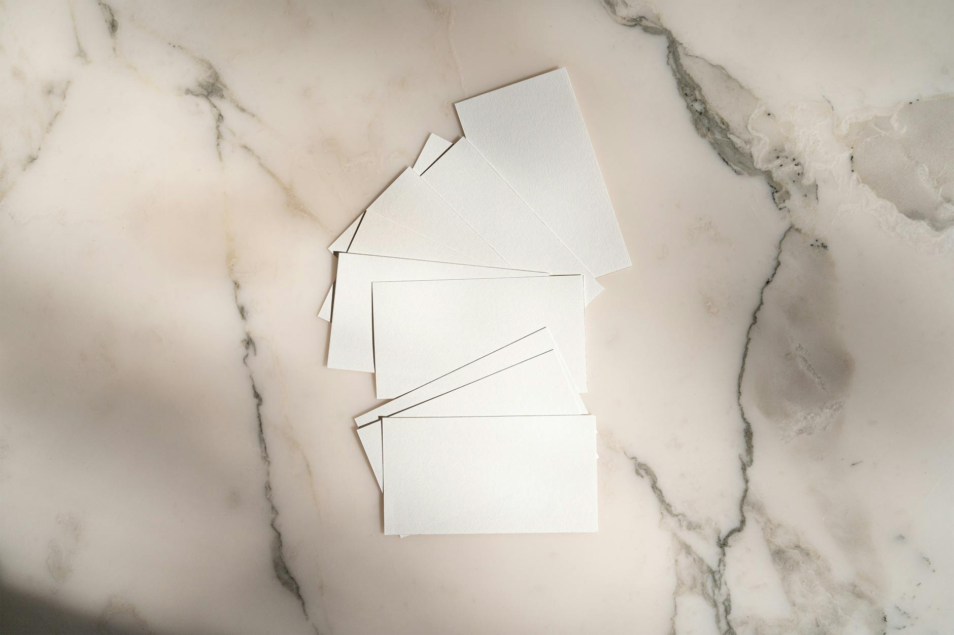 Close-up of square and standard rectangular business cards laid side by side on a white surface showing the size and shape contrast