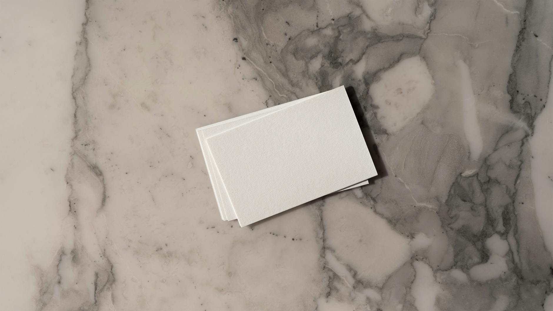Assorted square business cards with varied typography and design styles spread across a light timber surface