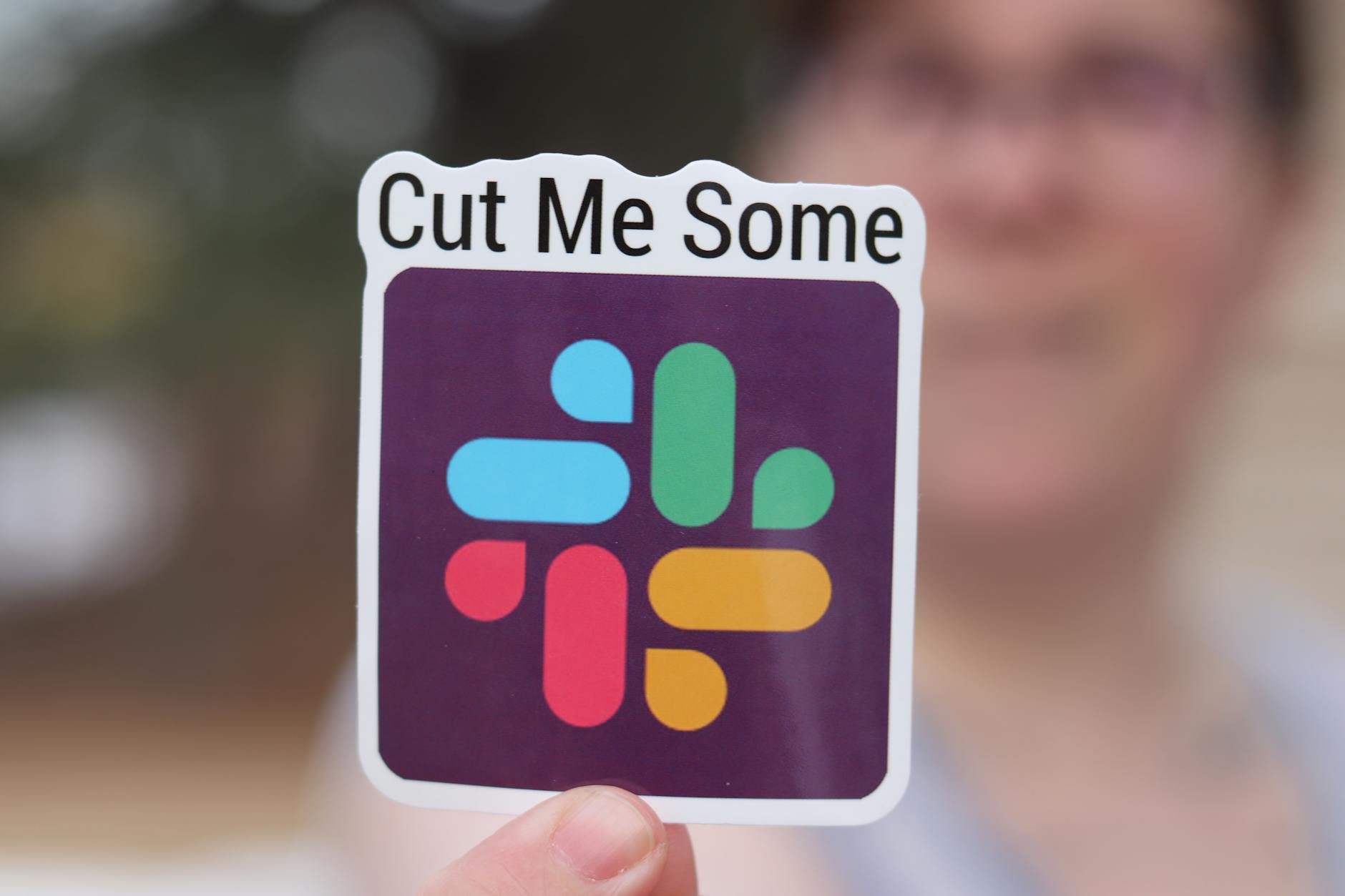 Close-up of a branded die-cut sticker being peeled from its kiss-cut backing sheet, showing crisp shape-cut lines and a smooth matte laminat