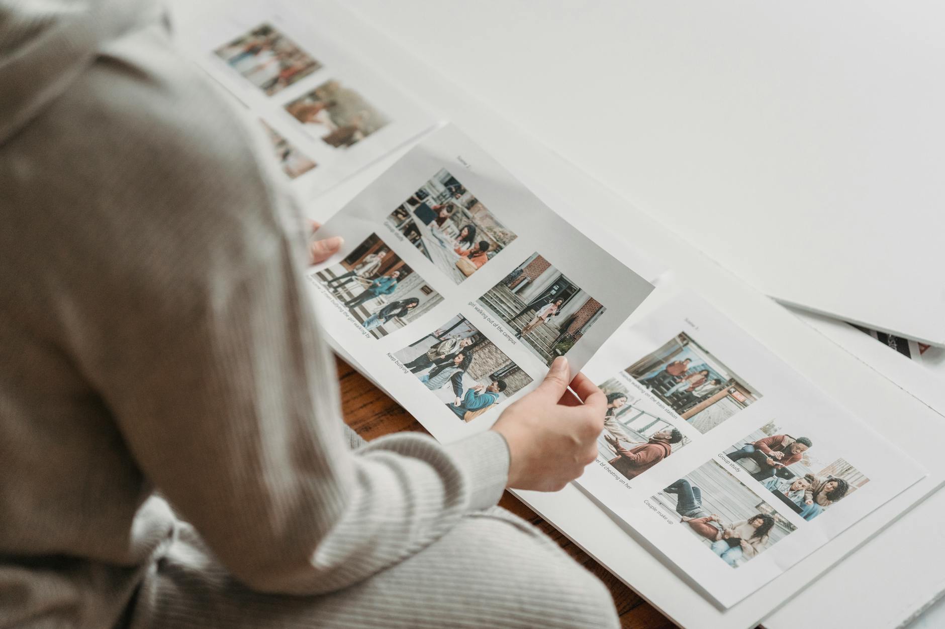 Print studio technician reviewing sticker sheet colour proofs on a wide monitor with printed sticker samples laid out on the desk alongside