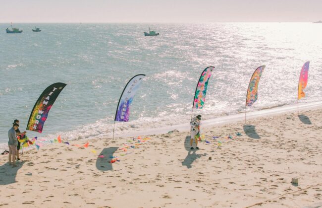 Teardrop banner outdoor event setup, large branded flag on ground spike at a corporate expo or sports event, daytime, outdoor setting