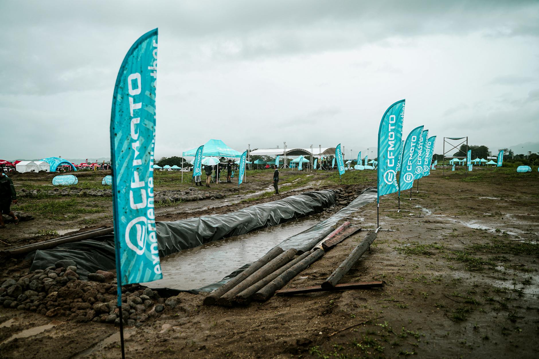 Teardrop banner and bow banner side-by-side at an outdoor event, showing the difference in shape and profile against a bright outdoor backgr