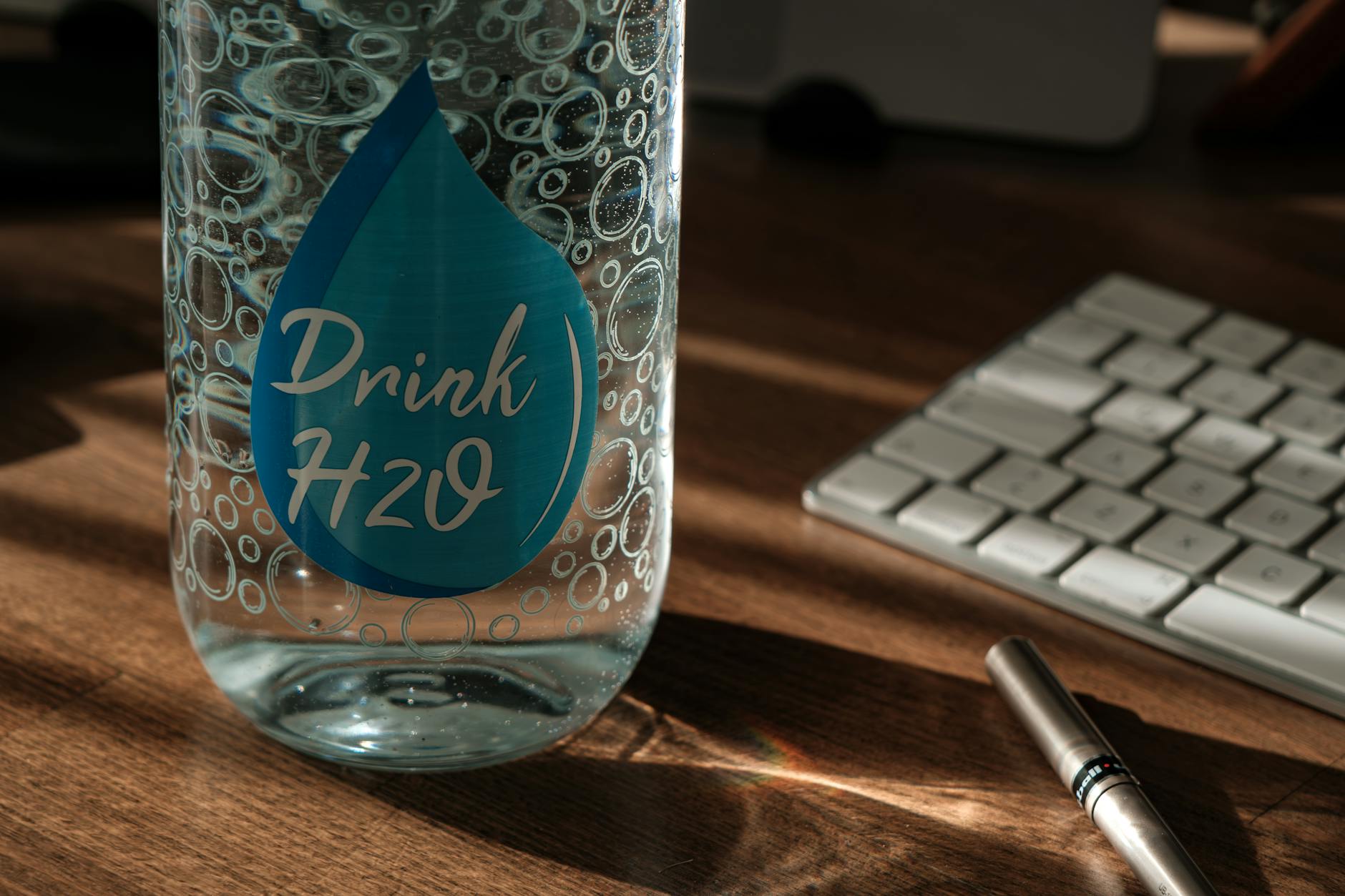close-up of a custom vinyl sticker on a reusable drink bottle, clear finish detail, styled flatlay with soft natural light