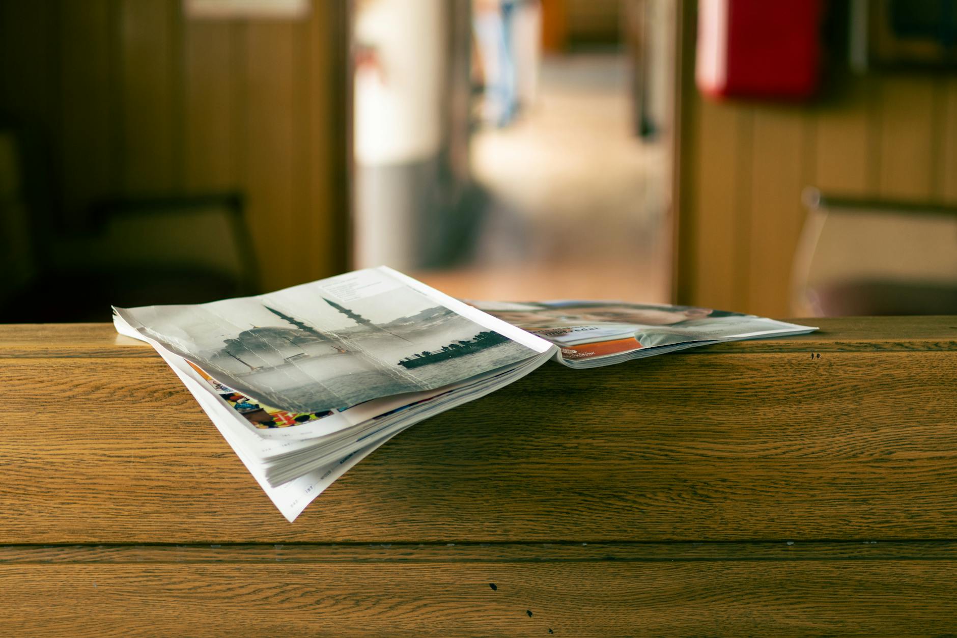 A saddle-stitched booklet open flat on a table beside a bound catalogue.