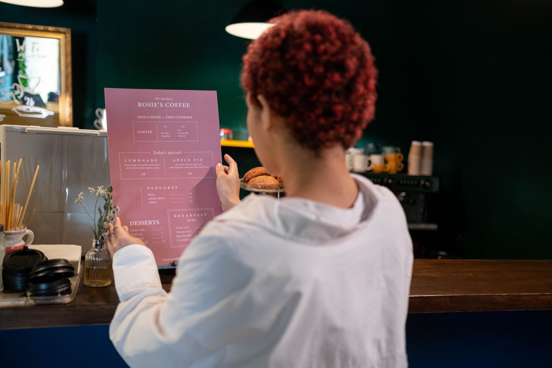 Close-up of a laminated 300gsm matte A4 menu being wiped clean with a cloth in a cafe setting, showing the wipe-resistant surface