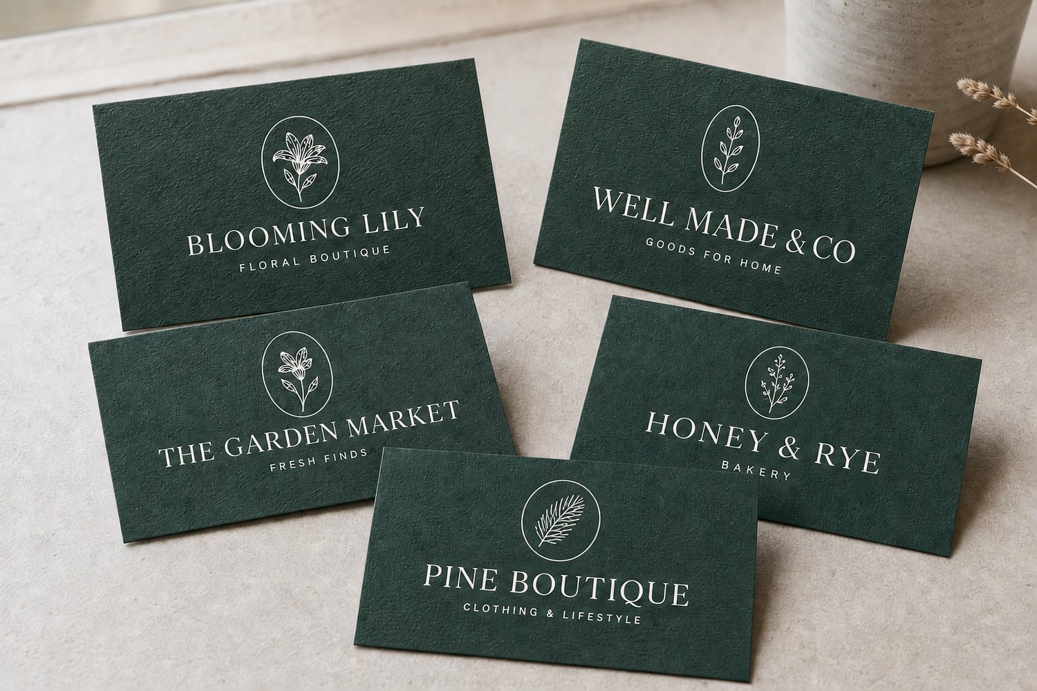 Business cards printed on textured forest-green felt/linen uncoated stock with the wordmark printed in crisp white ink.