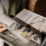 Hands turning the glossy printed pages of a magazine style catalogue
