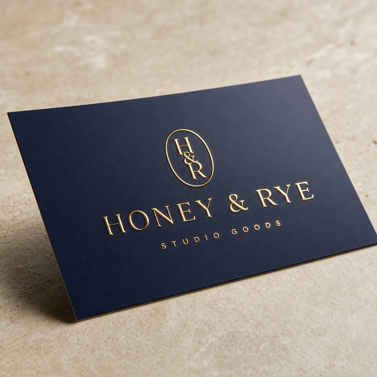 Business card, navy · 350gsm smooth stock · full-colour digital print · raised gold foil on wordmark