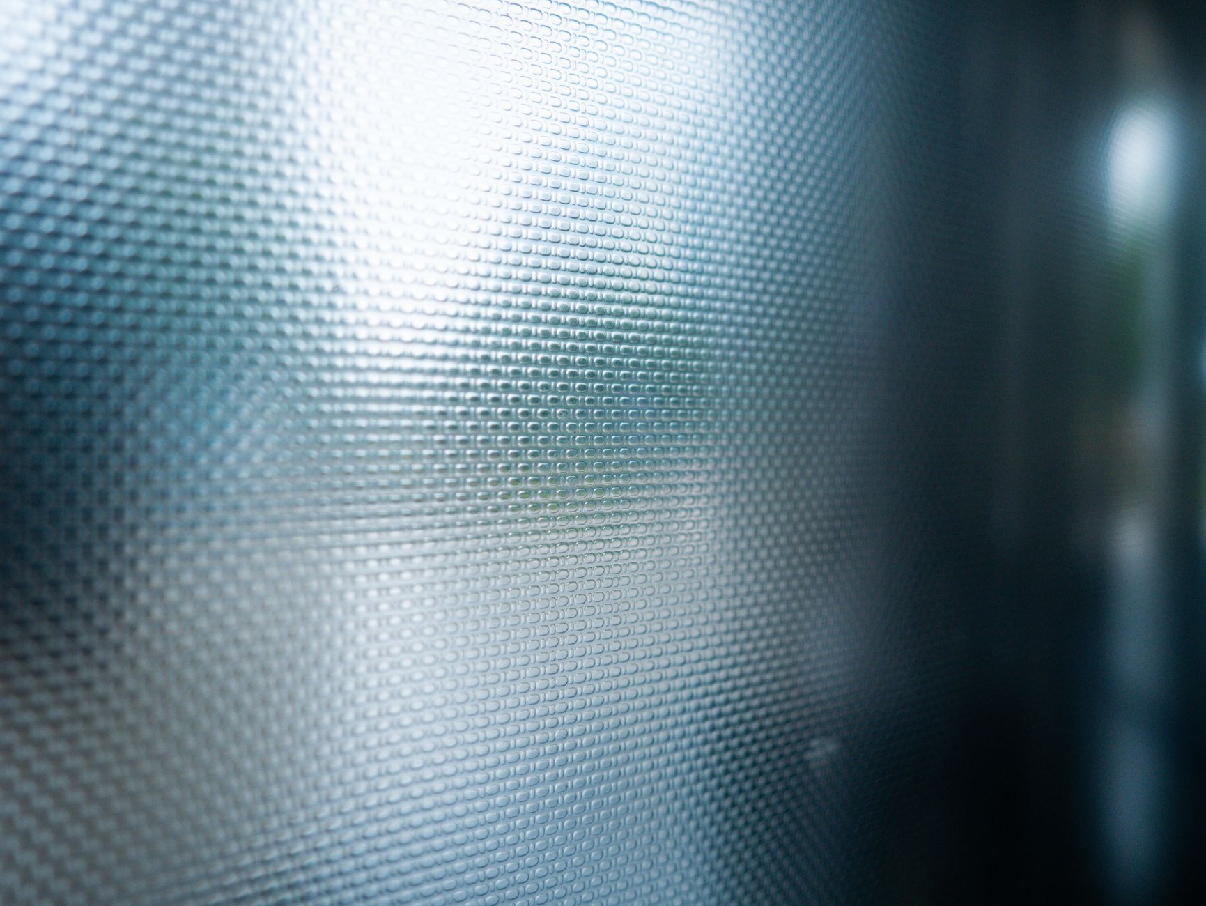Split-panel comparison showing the same office glass from outside: left half printed with one-way perforated window film showing a vivid
