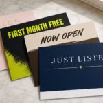 Premium fan of four different professionally printed rectangular marketing postcards on a light surface, illustrating the range of Australian postcard printing.
