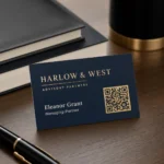A clean navy-and-gold accountant business card with name, title and a decorative QR code block, flat gold foil on laminated stock, modern office desk