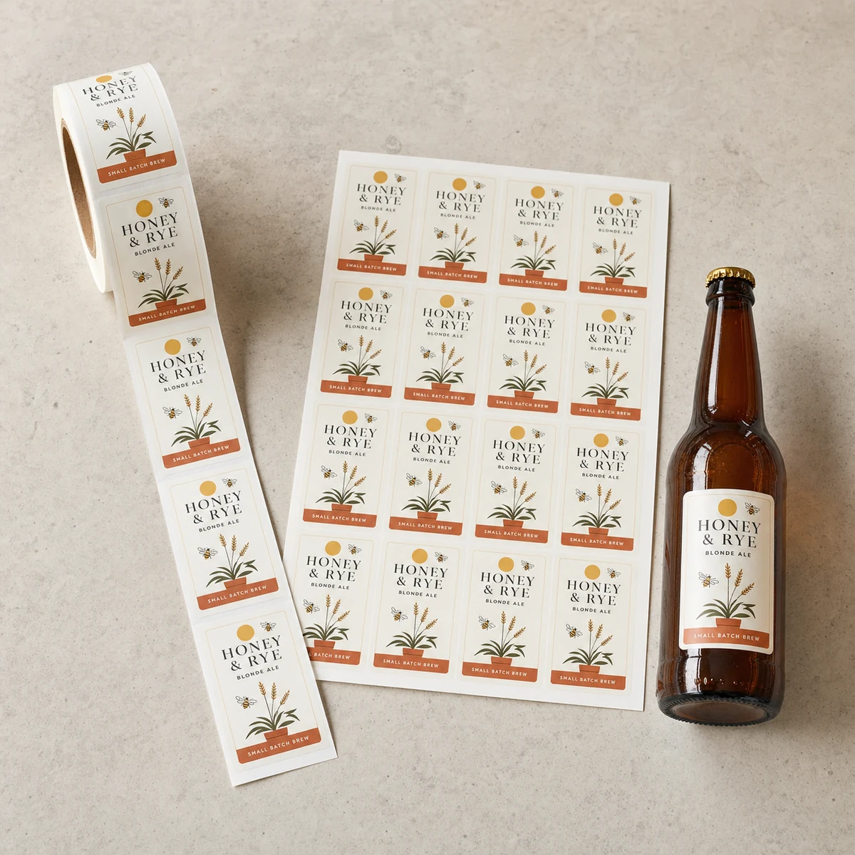 Overhead flat lay of a partly unspooled roll of craft-beer rectangle labels and a kiss-cut sheet of identical small labels beside a labelled bottle for scale, showing roll and sheet supply formats