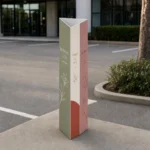 A custom-printed three-sided triangular corflute bollard sign sleeve standing on the ground around a yellow steel bollard in a clean shopping-centre carpark, full-colour branded faces