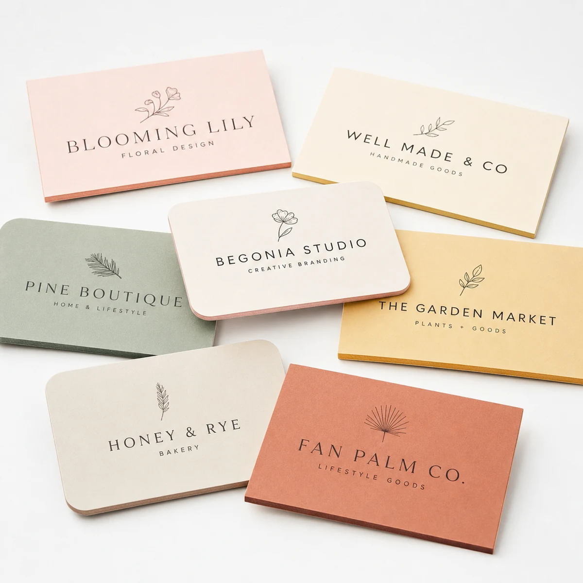 Scattered flat lay of thin duplex business cards in several designs and colourways, both rectangle and rounded-corner formats, the slim two-ply edges visible
