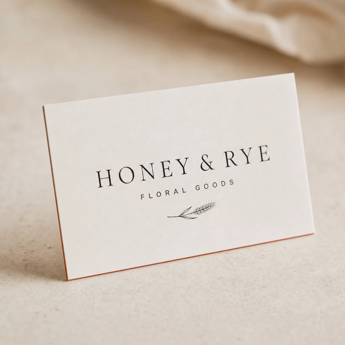 A single thin duplex business card propped upright with black typography on a clean white face, its wallet-slim two-ply profile and fine two-tone cut edge visible