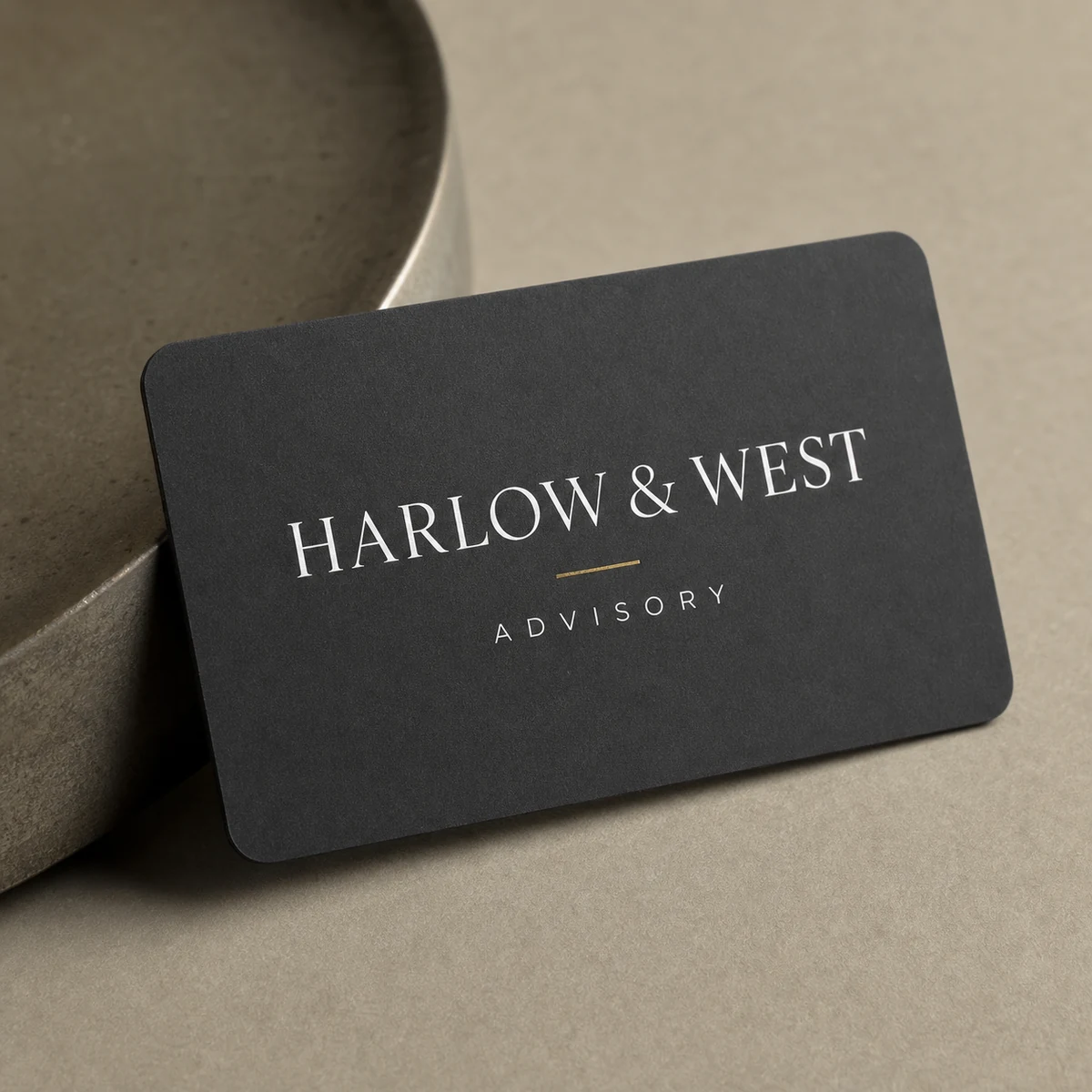 Close-up of a charcoal law-firm business card with white-ink typography and rounded corners, showing the matte finish and crisp cut edge