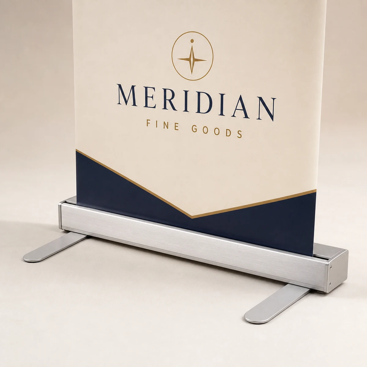 Close-up of a premium retractable banner's flat brushed-aluminium cassette base with the vinyl panel feeding into the housing slot, showing the bottom dead-zone, with exactly two forward paddle feet, one at each end