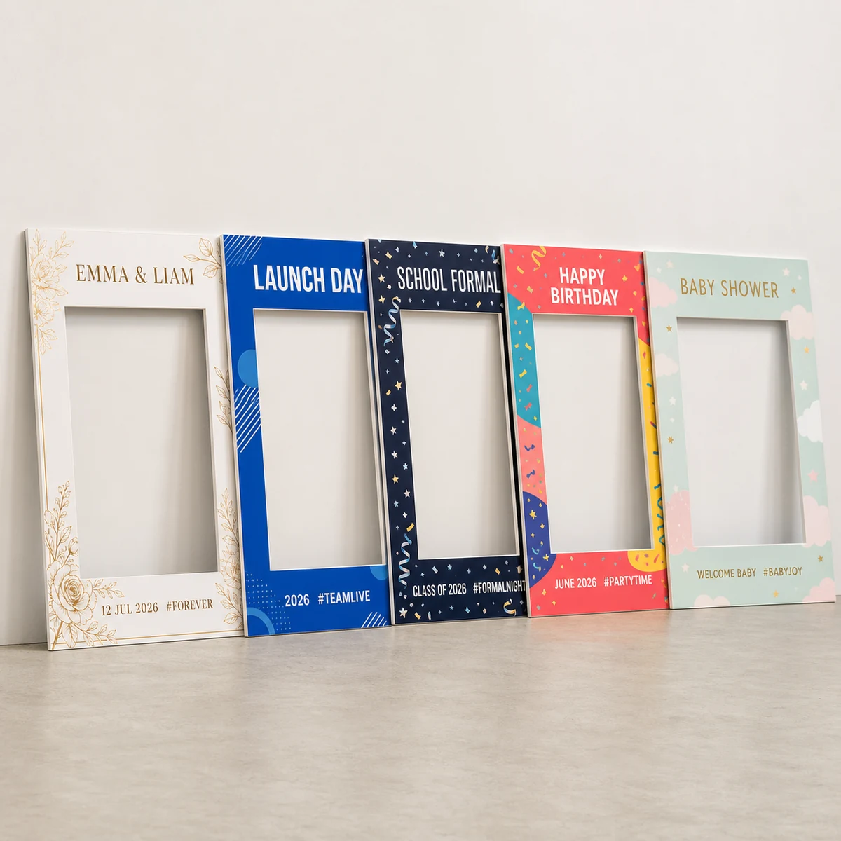 Five custom selfie frames leaning against a wall in a print studio in varied event designs, wedding, corporate and school formal, the 5mm foamboard cut edges visible