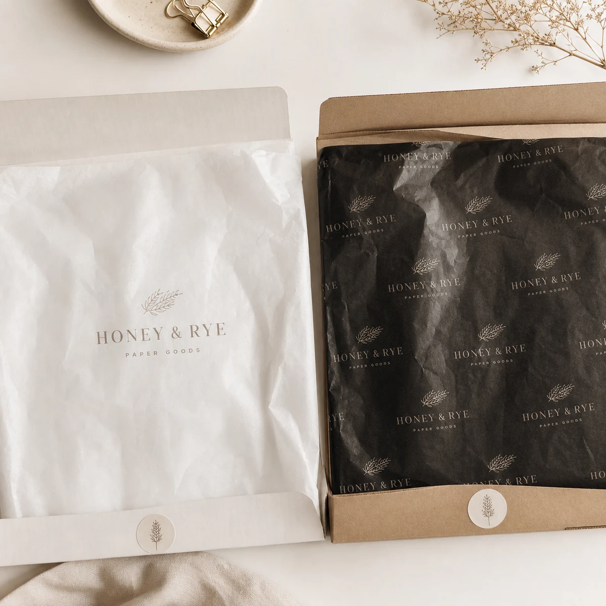 Side-by-side overhead comparison of two tissue sheets, a light single-colour logo print next to a dense full-coverage dark print, showing the colour density difference