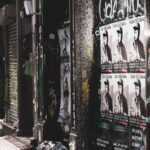 layered gig and event posters pasted on a street wall
