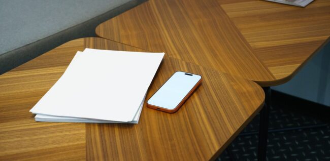 a stack of A5 saddle-stitch booklets with a gloss laminate cover fanned out on a white table in a studio setting